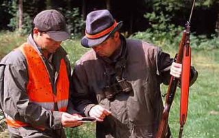 Ein Förster und ein Forstarbeiter beim Reviergang vor dem Wald.