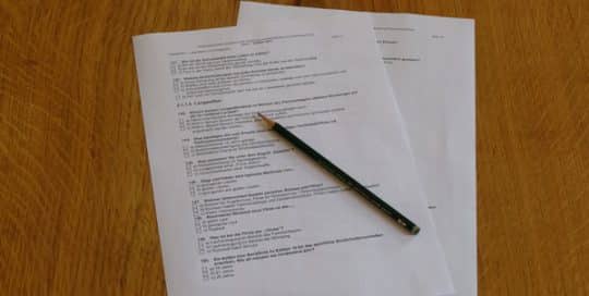 Ein Prüfungsbogen liegt mit einem Bleistift auf einem Tisch.